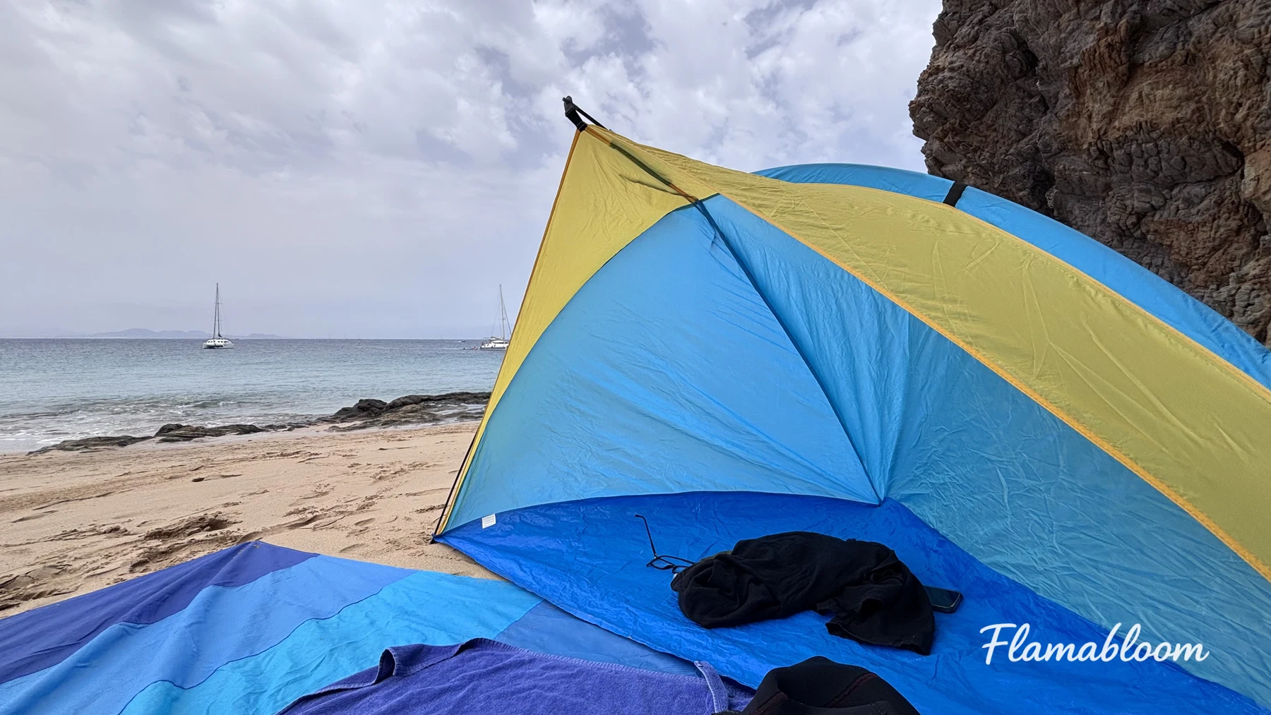 Một tấm chắn gió màu xanh vàng đặt trên bãi cát gần biển ở Lanzarote.