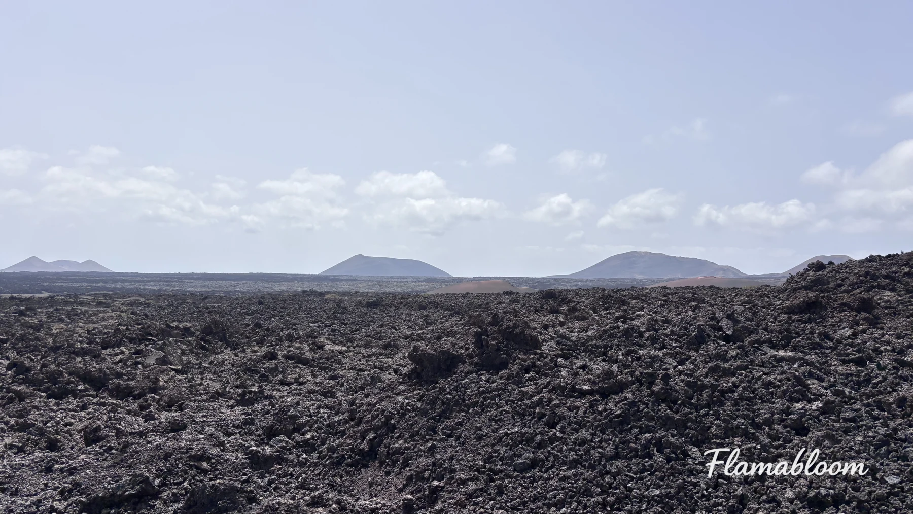 Vùng đất núi lửa đen ở Lanzarote với những ngọn núi thấp dưới bầu trời sáng.